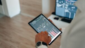 Close-up of hands using a tablet for online trading and market analysis.
