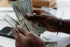 Detailed image of hands counting US dollar bills on a desk, emphasizing finance and budgeting.