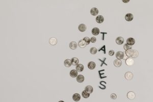 Scattered coins forming the word 'TAXES' on a white surface, symbolizing financial concepts.